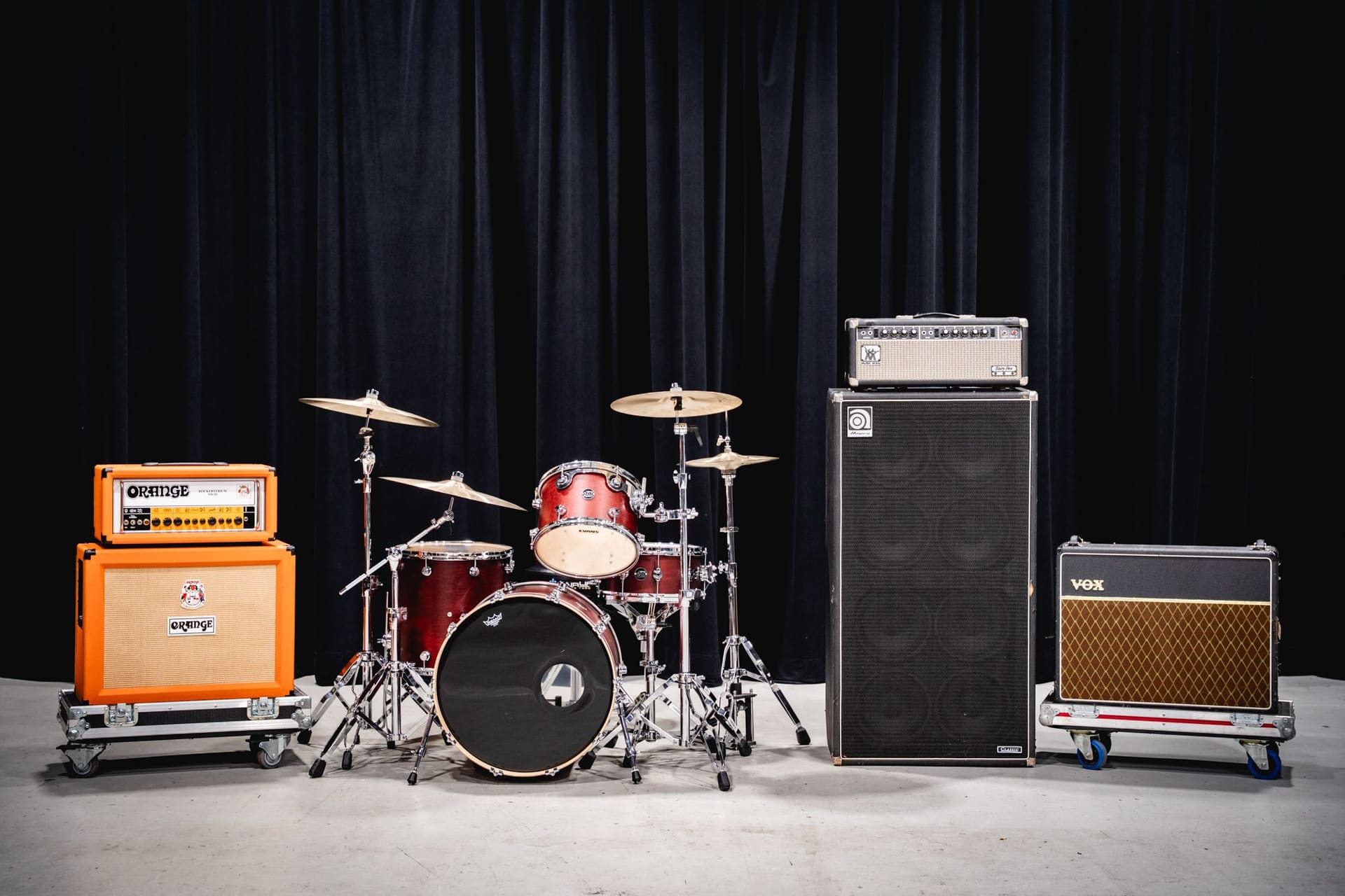 Stage backline: drum kit flanked by guitar and bass amp stacks